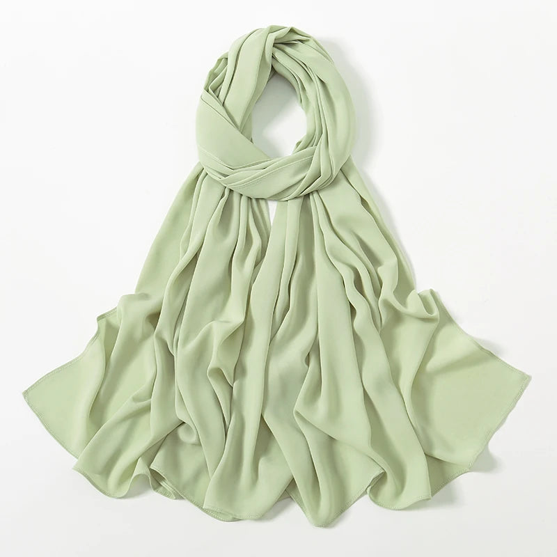 Helles salbeigrünes Chiffon-Schal in fließender, plissierter Form.