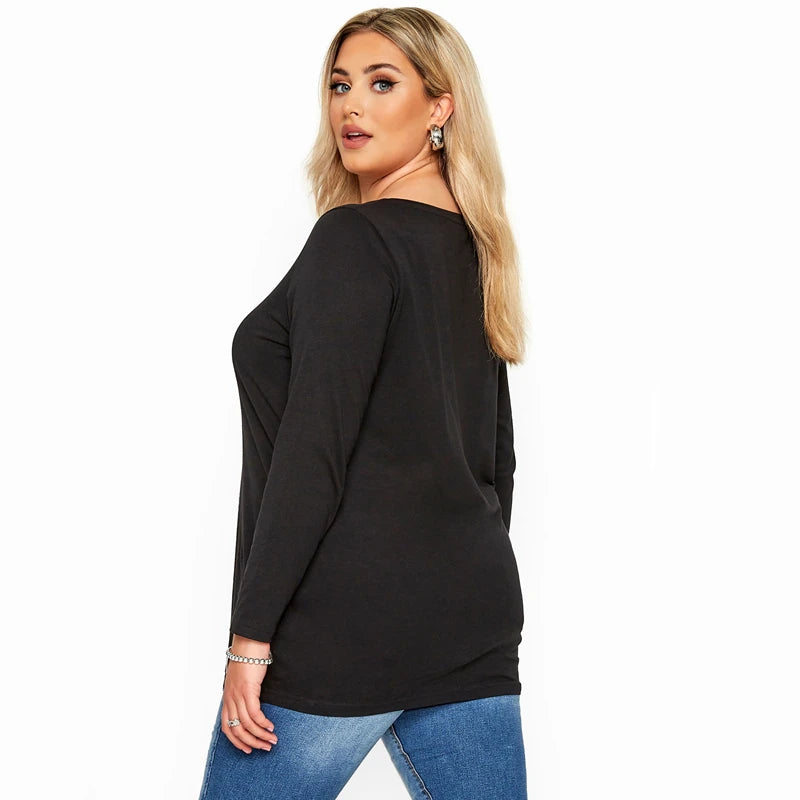 Une femme modélise un élégant t-shirt noir à manches longues en coton avec un jean bleu.