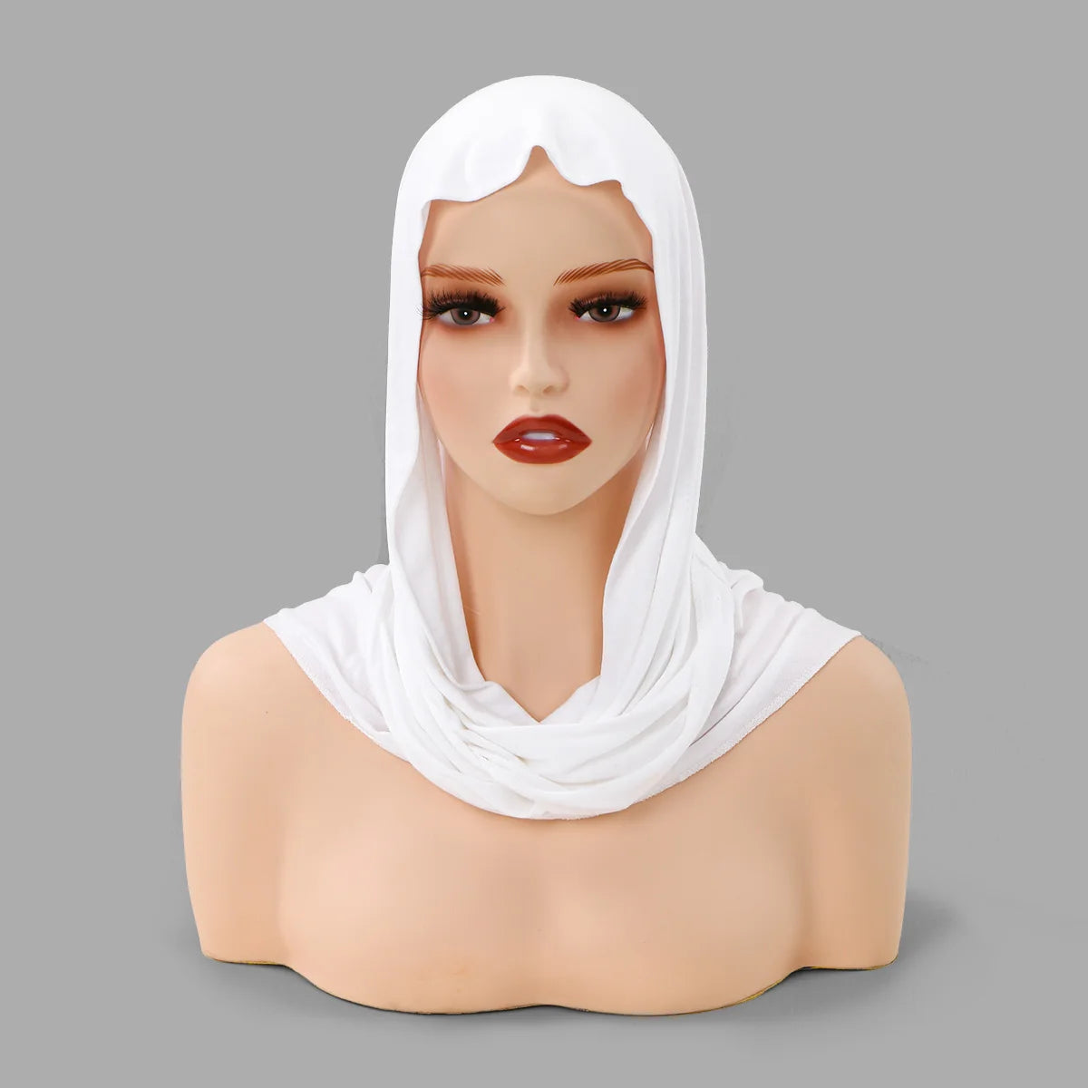 Eine Mannequin zeigt einen weißen Hijab-Schal, der um Kopf und Hals drapiert ist.