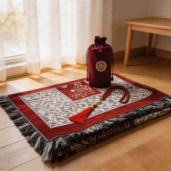 A red and white prayer rug set with a tasbih and a matching carry bag displayed on a wooden floor.