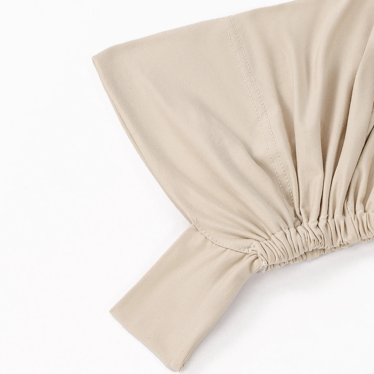 Gros plan d'un foulard hijab beige uni, montrant le détail du tissu froncé.