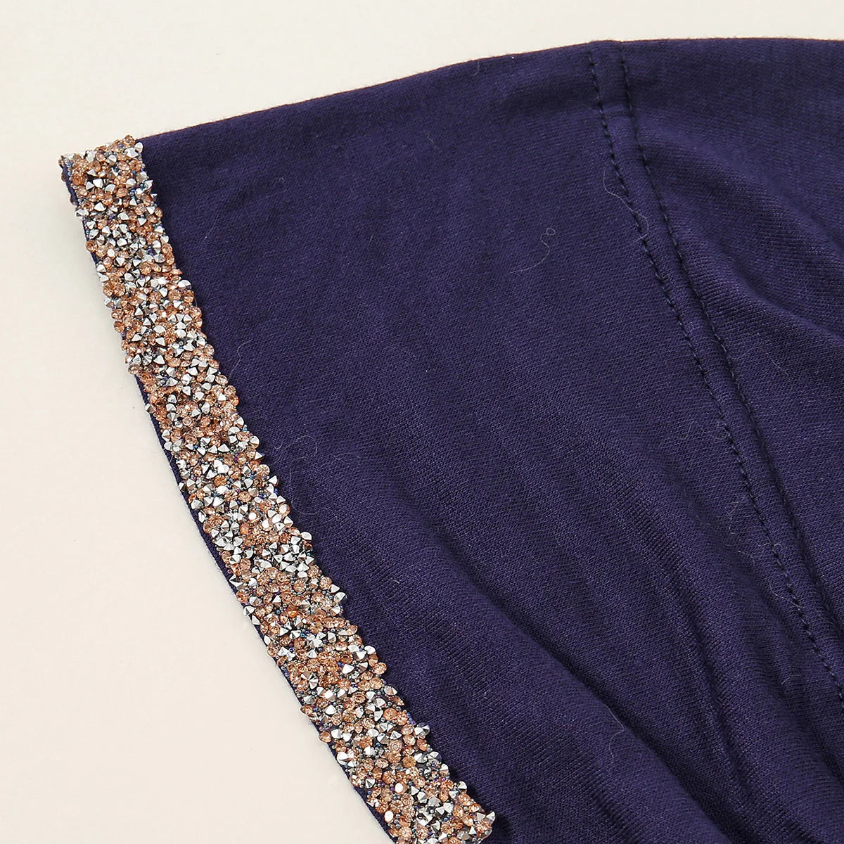 Nahaufnahme eines dunkelvioletten muslimischen Hijab-Schals mit funkelnder Strasskante am Rand.