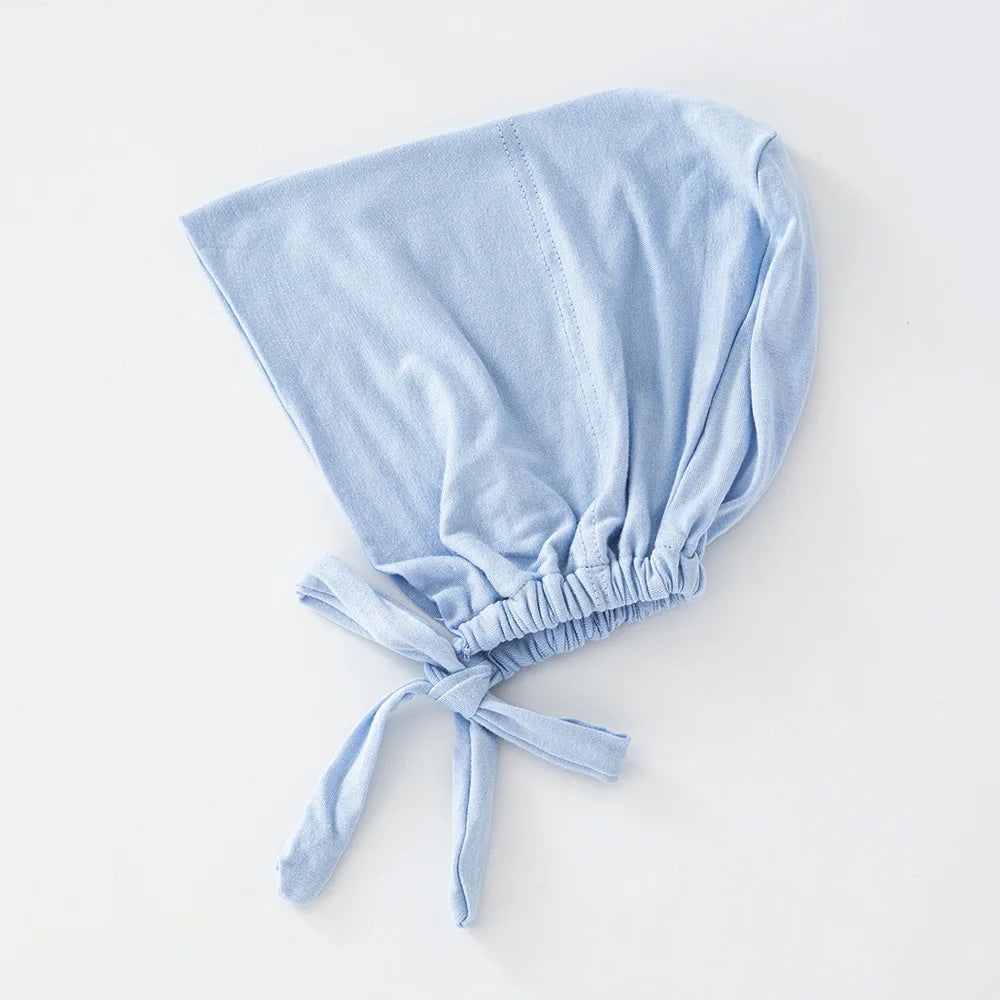 Hellblaue Schleier-Bindung, Innihجاب-Bonnet, gefaltet auf einer weißen Oberfläche.