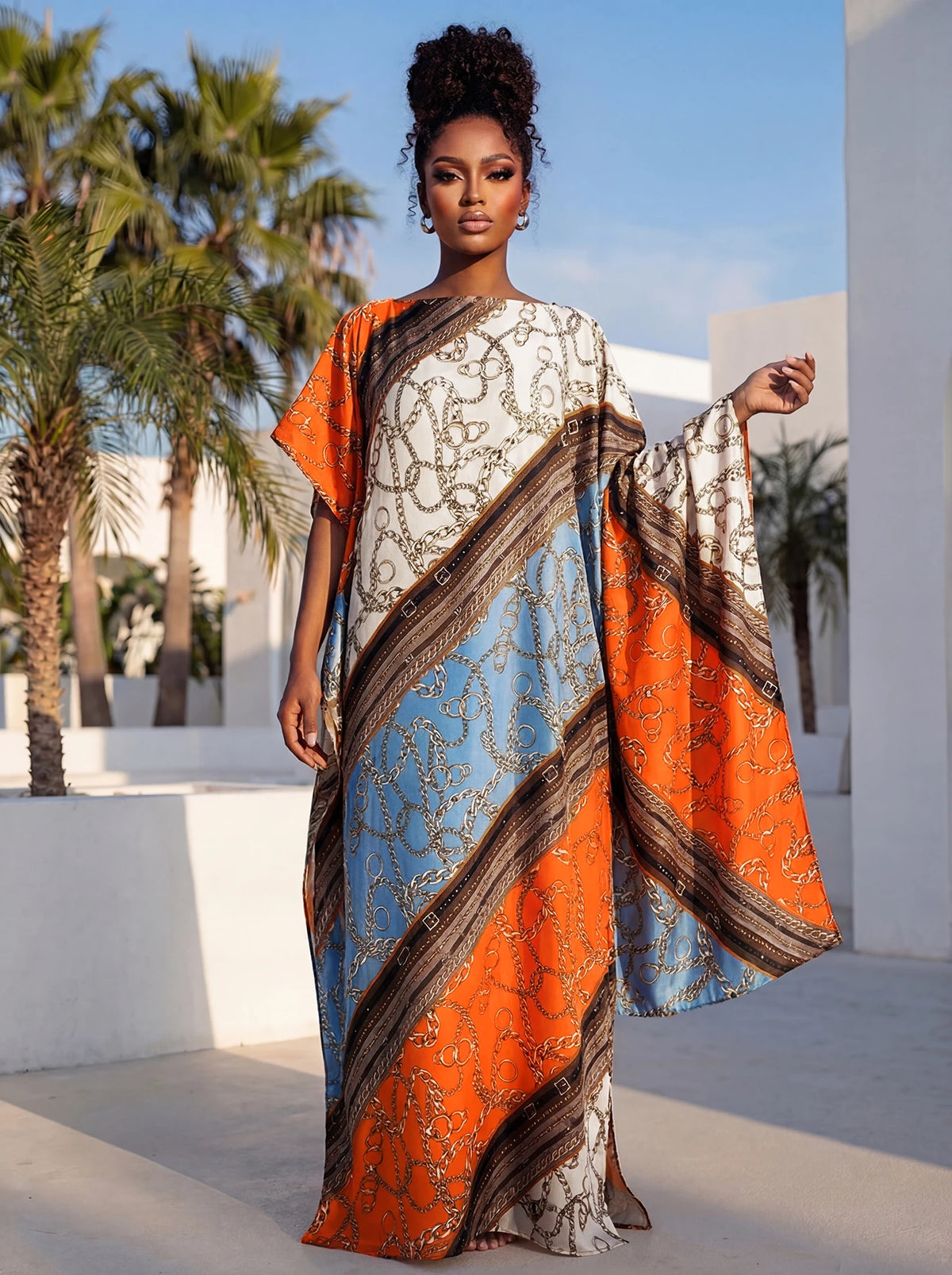 Eine Frau modelliert ein elegantes bedrucktes Seidenkaftan-Kleid in orange- und blauen Tönen im Freien.