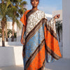 Eine Frau modelliert ein elegantes bedrucktes Seidenkaftankleid in Orange-, Blau- und Beige-Mustern im Freien.