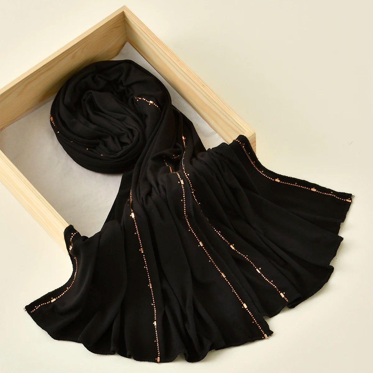 Pañuelo de jersey de algodón con brillo negro, enrollado y drapeado en un marco de madera.