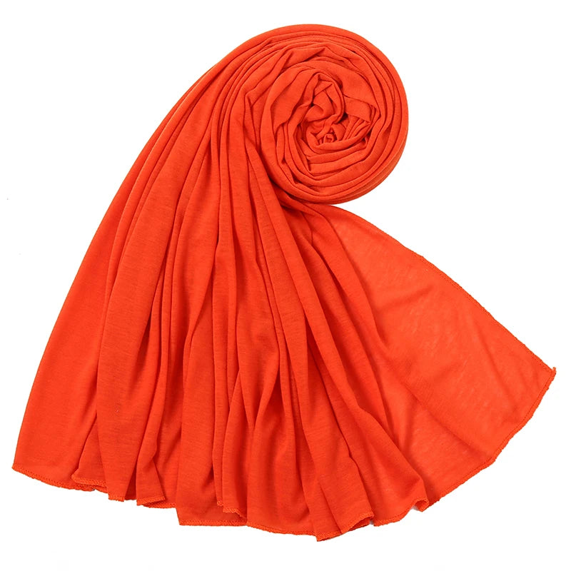 Leuchtend orange Baumwoll-Jersey-Hijab-Schal in Spiralform gerollt und drapiert