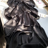 Verdunkeltes schwarzes Crinkle-Satin-Chiffon-Hijab-Stoff auf weißem Untergrund.