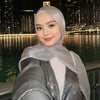 Femme portant un châle hijab en mousseline crinklée argentée et scintillante, regardant l'appareil photo contre un paysage ur