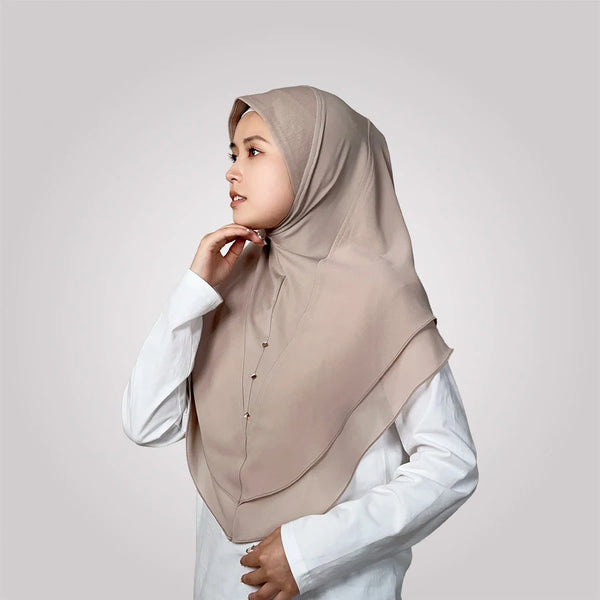 A woman wearing a beige chiffon double-layered instant hijab scarf, looking to the side.