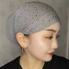 Nahaufnahme einer Frau mit grauem elastischem Turbanhut, verziert mit kleinen Strasssteinen.