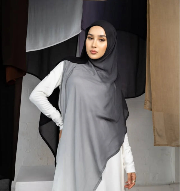 A woman wearing a gray elegant gradient rayon modal hijab scarf and white clothing.