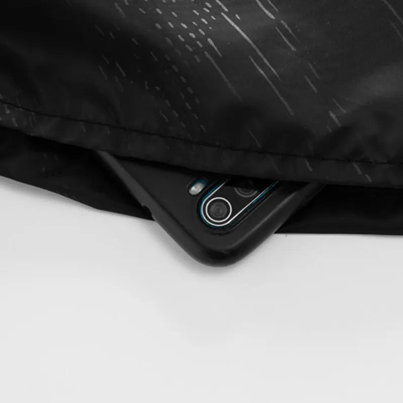 Nahaufnahme einer schwarzen wasserdichten Wanderhose mit einem Smartphone darunter.