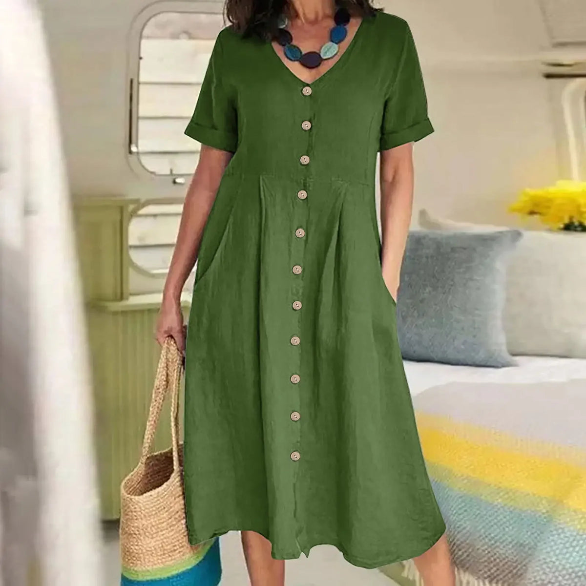 Eine Frau trägt ein olivgrünes Baumwoll- und Hanf-V-Ausschnittkleid mit kurzen Ärmeln und Knopfleiste.