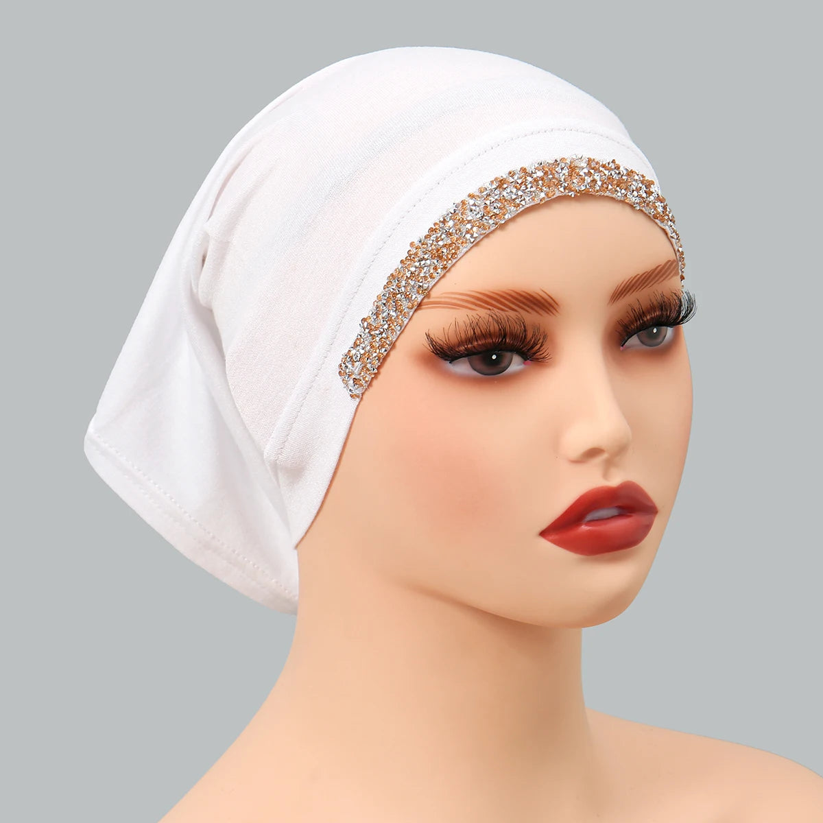 Modelo vistiendo un hiyab interior elástico de algodón modal blanco decorado con bordado de purpurina dorada en la frente.