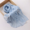 Écharpe de mousseline bleu clair froncée drapée et pliée sur un cadre en bois.