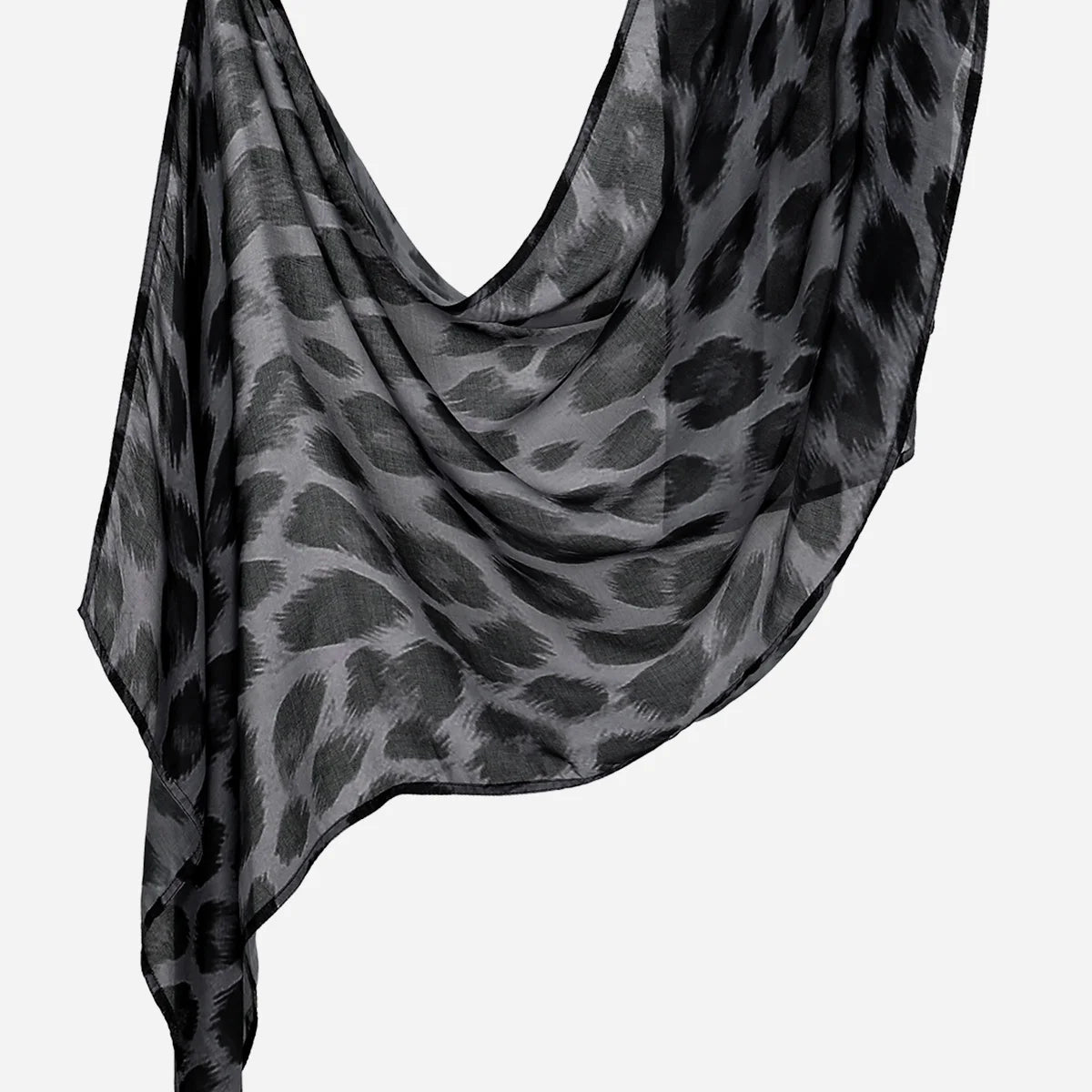 Durchsichtiger schwarz-grauer Leopard-Print-Leinen-Baumwoll-Hijab-Schal, über einer Oberfläche drapiert.
