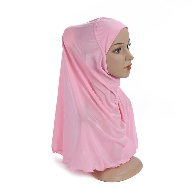 Un chal/pañuelo rosa para niños de Ramadán drapeado sobre la cabeza de un maniquí.