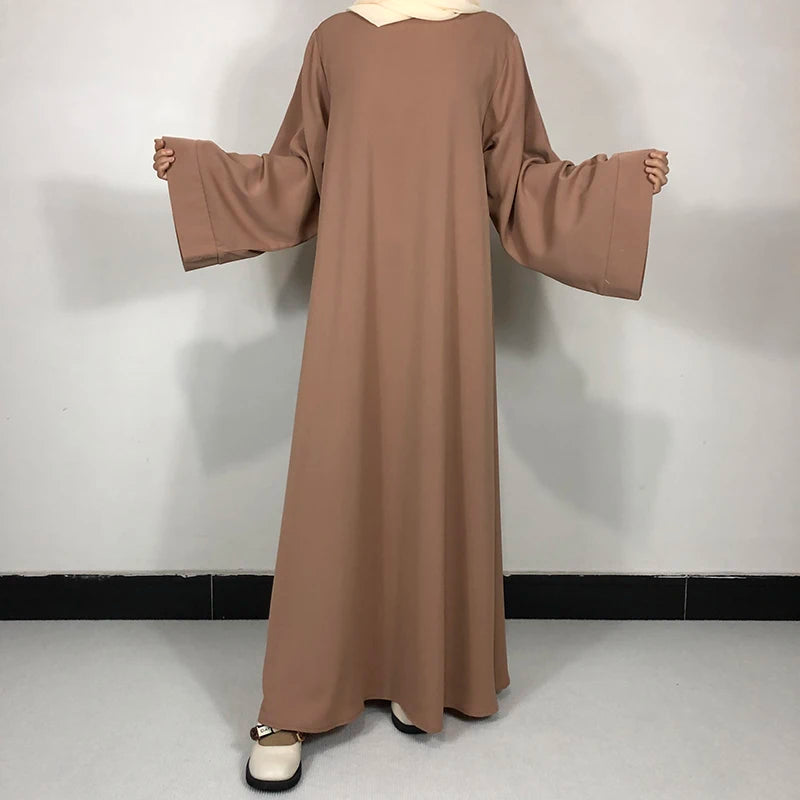 Une longue robe Nida Abaya marron et fluide présentée sur un mannequin.