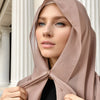 Eine Frau trägt einen beigen Instant-Chiffon-Hijab und blickt direkt in die Kamera.
