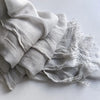 Une pile de foulards de hijab en viscose coton doux gris clair avec pompons.