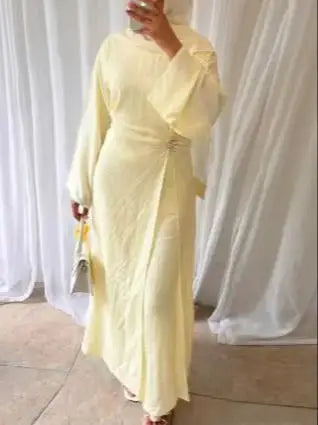 Une femme portant une abaya jaune uni à cordon, vue de corps entier.