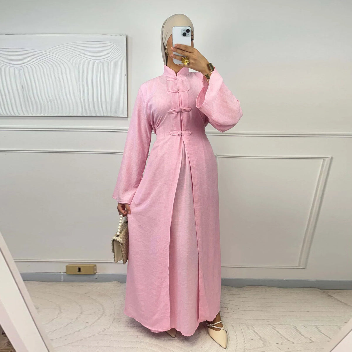 A woman models a pink elegant two-piece Arabic modest set with long sleeves and a high collar.