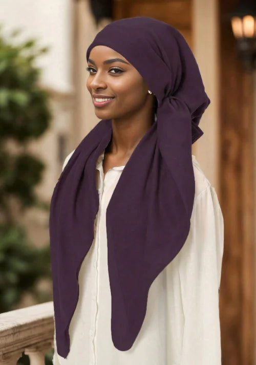 Mujer usando una diadema elástica de diamantes morados profundos para hijab, sonriendo y mirando a un lado.