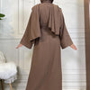 A woman wearing a long, earth-toned abaya and kaftan set with a hood, shown from the back.