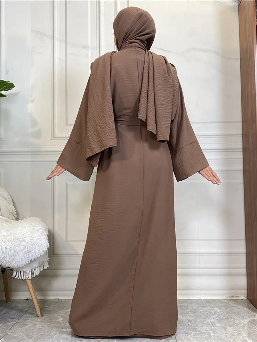 A woman wearing a long, earth-toned abaya and kaftan set with a hood, shown from the back.