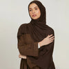 A woman wearing a solid brown stretchy jersey plain hijab scarf.