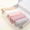 Ein Set von fünf einfarbigen Jersey-Hijab-Schals in Beige, Weiß, Pink und Grau, ordentlich gefaltet in einer weißen Box.