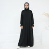 Una mujer vistiendo un vestido abaya negro, suelto y fluido, para la oración.