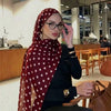 Eine Frau trägt einen roten Polka-Dot-Baumwollschal und schwarze Kleidung und blickt in die Kamera.