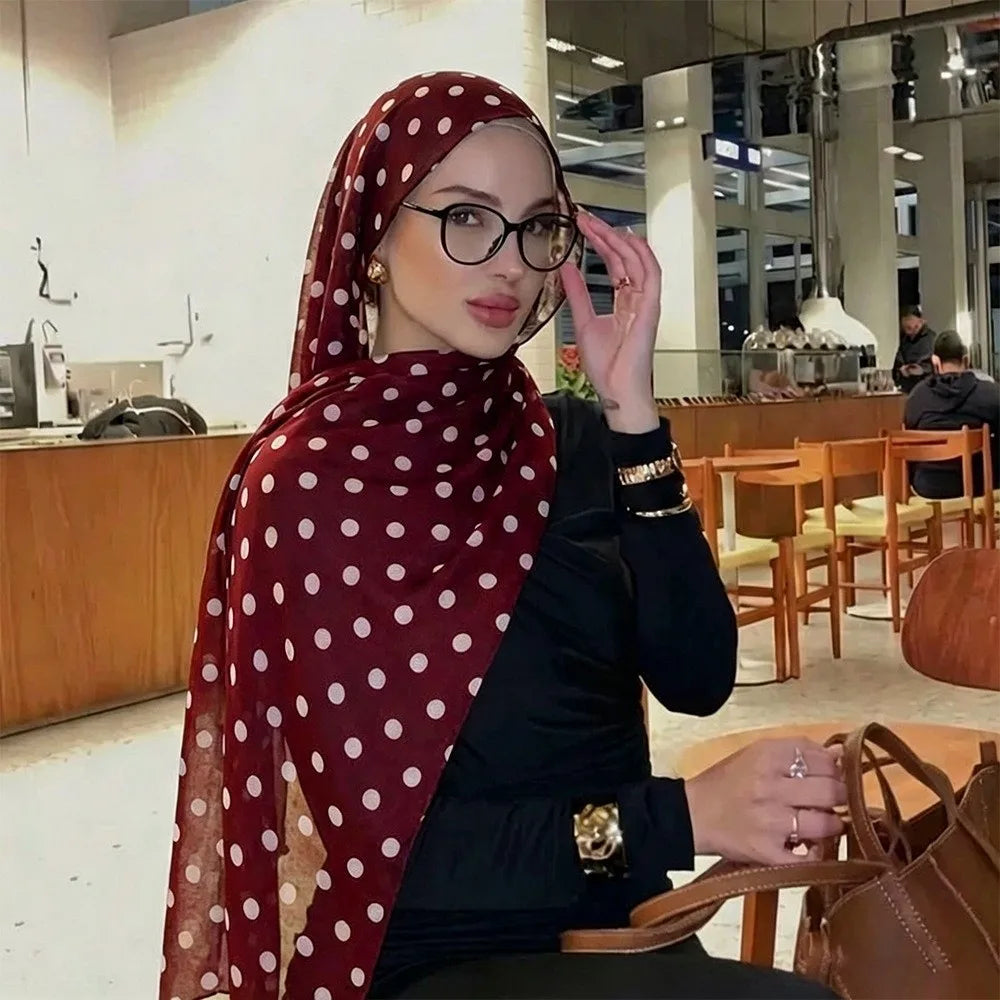 Eine Frau trägt einen roten Polka-Dot-Baumwollschal und schwarze Kleidung und blickt in die Kamera.