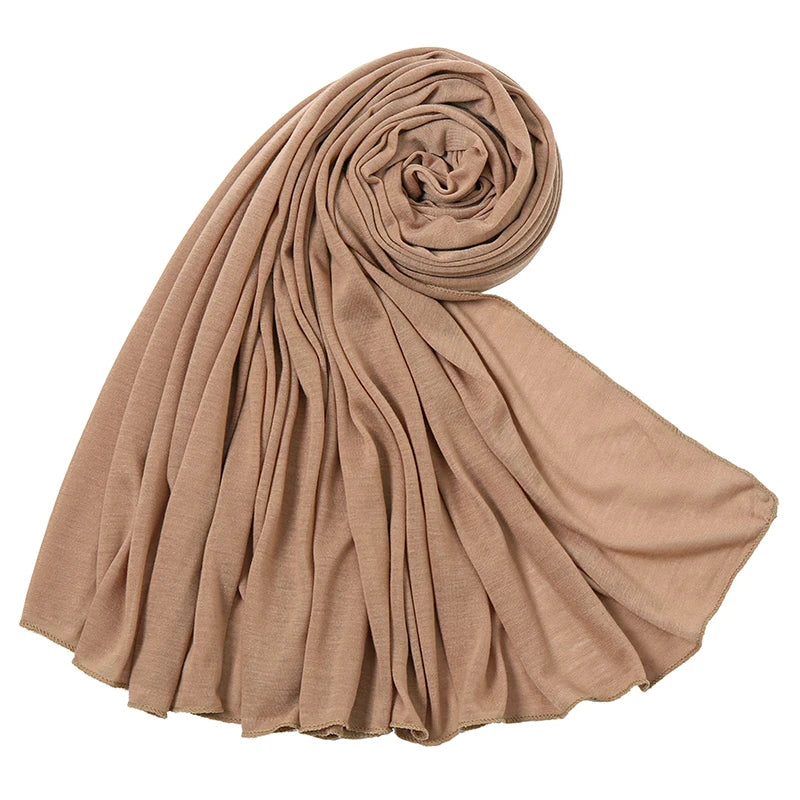 Beige Baumwoll-Jersey-Hijab-Schal, gerollt und drapiert, zeigt seine weiche Textur und den Fall.