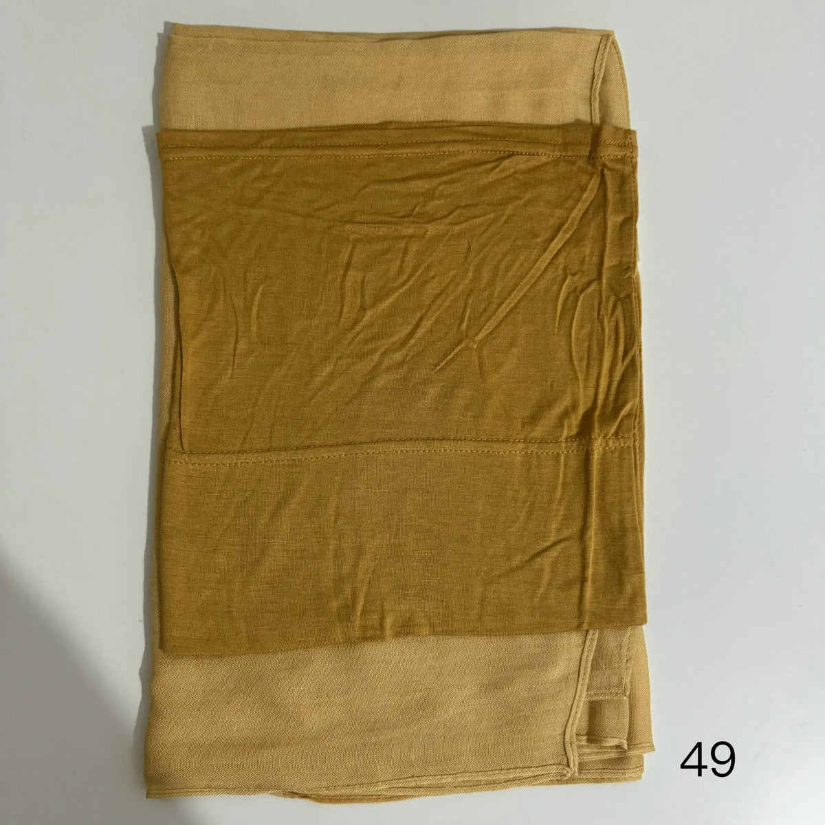 A stack of three solid mustard yellow fabric pieces, likely a hijab set made of soft modal rayon.