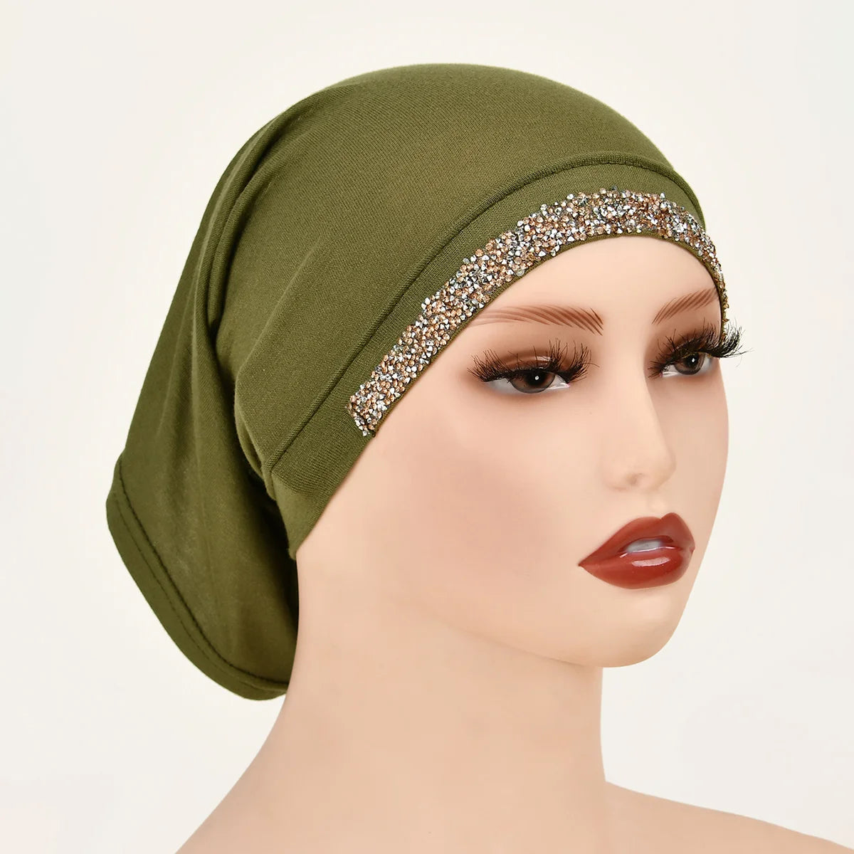 Una modelo lleva un hiyab interior de algodón elástico modal verde oliva con un ribete dorado brillante.