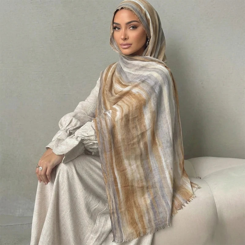 Una mujer vistiendo un pañuelo hijab a rayas acuareladas beige y marrón y un atuendo a juego.