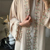 Elegante beige Abaya mit dezenter grüner und rosa Blattstickerei auf der Vorderseite.