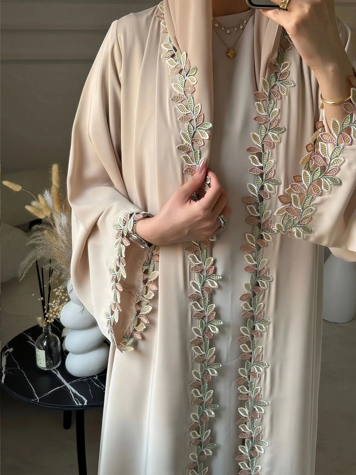 Elegante beige Abaya mit dezenter grüner und rosa Blattstickerei auf der Vorderseite.