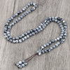 Silber- und schwarze Natursteinperlenkette mit strukturierten sphärischen Perlen auf Holzoberfläche.