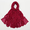 Écharpe châle crêpe rouge profond drapée et pliée sur fond blanc.
