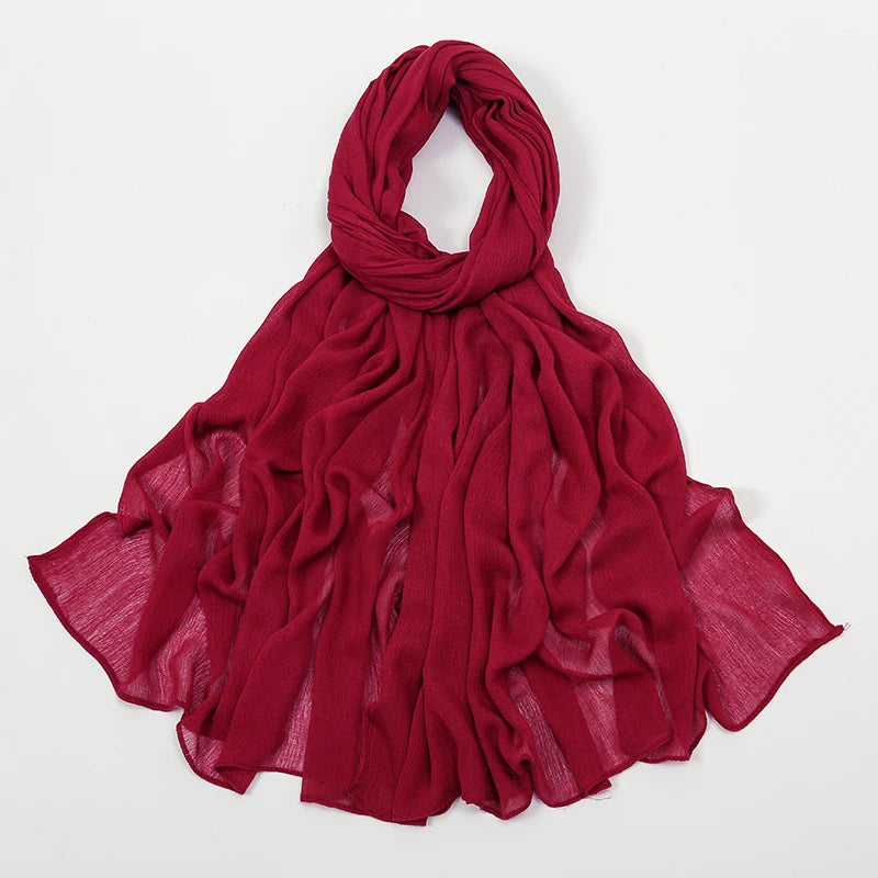 Écharpe châle crêpe rouge profond drapée et pliée sur fond blanc.