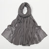 Écharpe foulard en crinkle gris drapée autour du cou et des épaules.