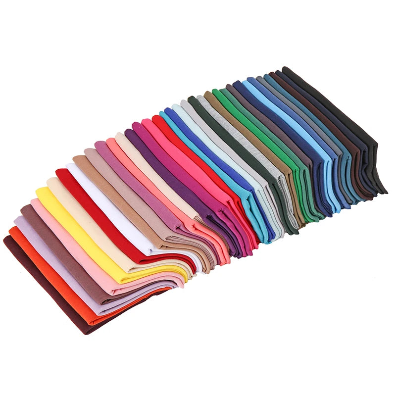 Eine Sammlung gefalteter Damen-Jersey-Hijab-Schals in verschiedenen Pink-, Rot-, Grün-, Blau- und Brauntönen.