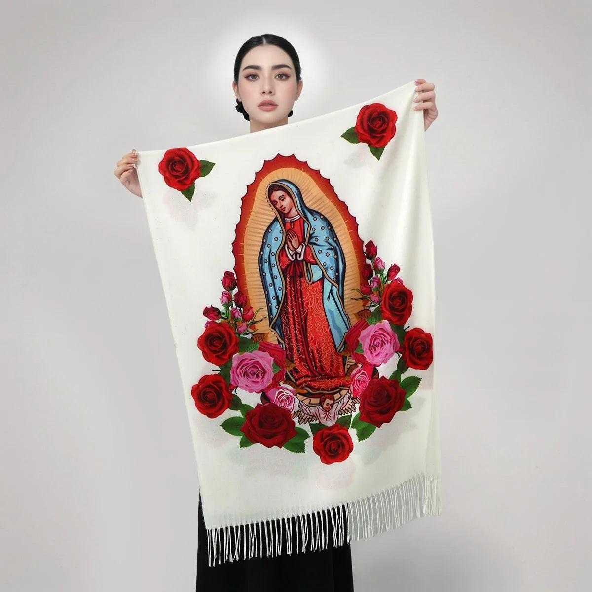 Una mujer sostiene una bufanda impresa personalizada con la Virgen de Guadalupe en rosas rojas y rosadas sobre fondo blanco.