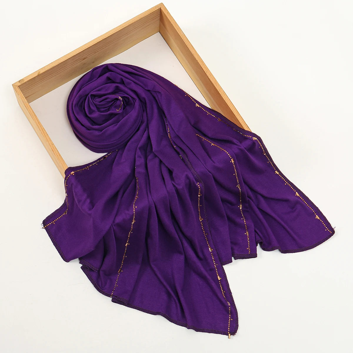 Pañuelo de jersey de algodón con brillo morado intenso, drapeado sobre un marco de madera.