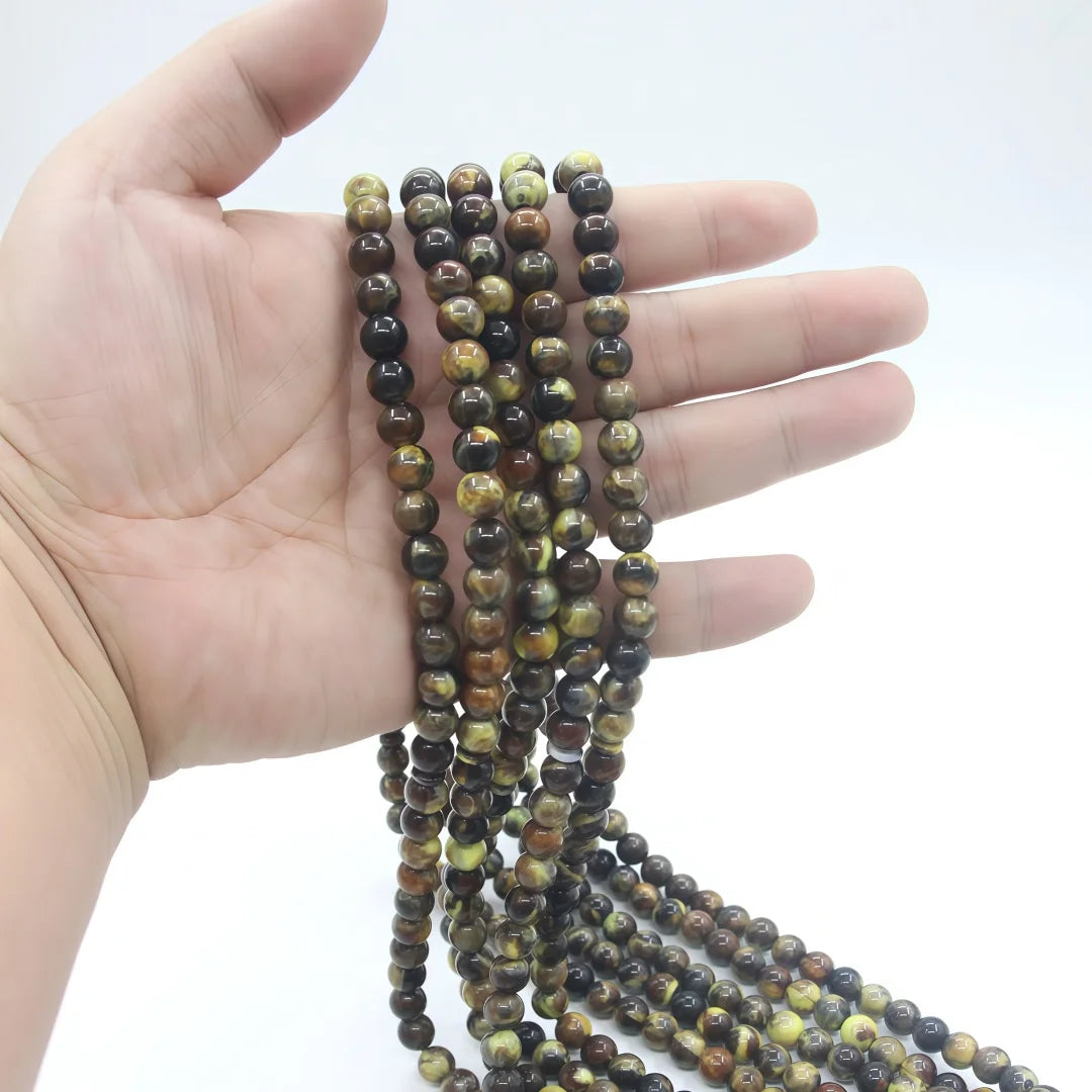 Una mano sostiene una cuenta de cuentas marrón oscuro y doradas para oración musulmana (tasbih).