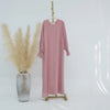 Vestido abaya oversize color rosa empolvado colgado en percha de madera contra fondo blanco.